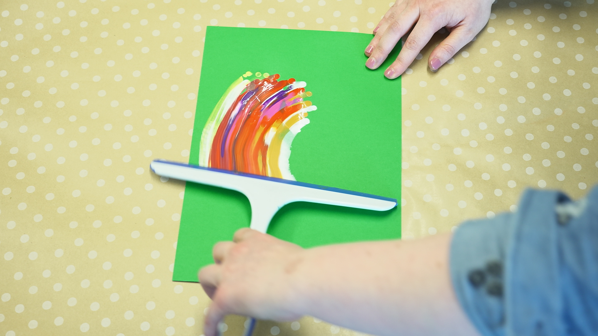 A squeegee being used to paint on a piece of paper