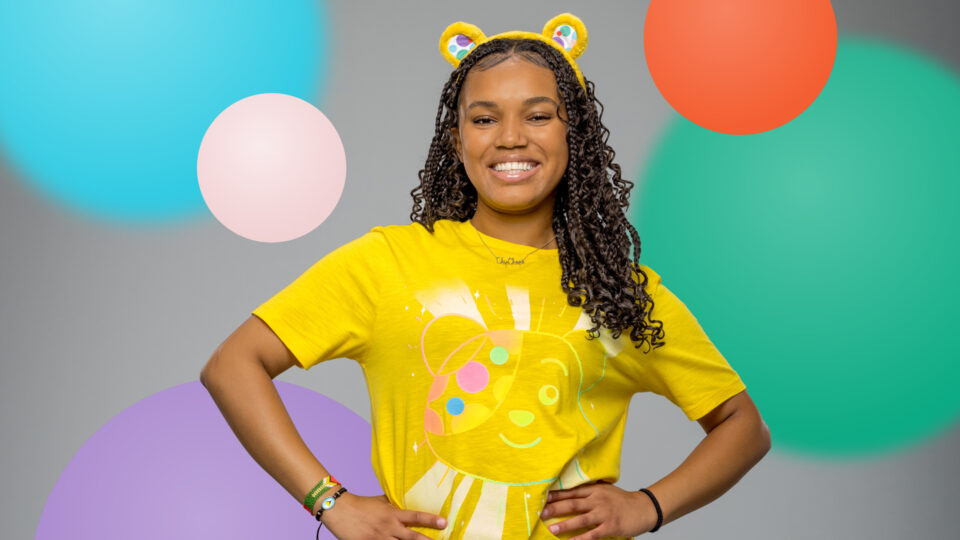 Tanisha smiling against a spotty background wearing Pudsey ears and a Pudsey t-shirt