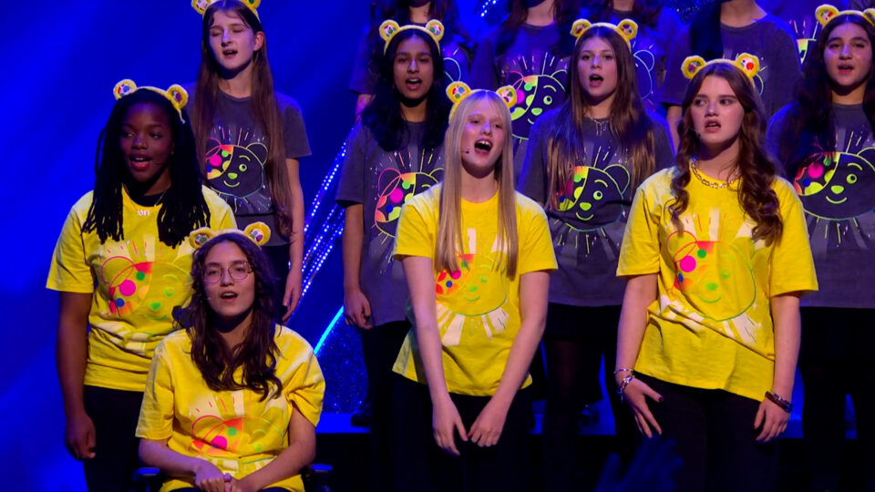 Children in yellow Pudsey t-shirts singing