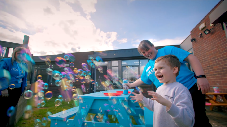 A child smiling as they play with bubbles