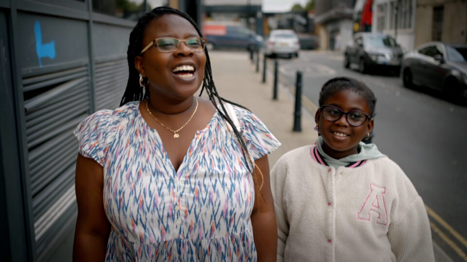 A lady and child smiling, walking in the street