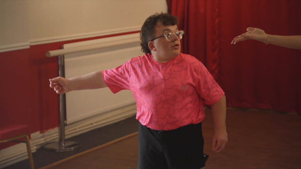 Ethan practising a dance routine in front of a red curtain