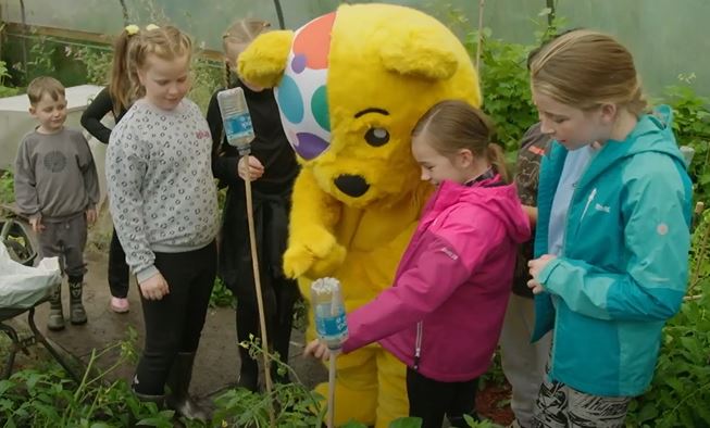 Pudsey with some children in a garden