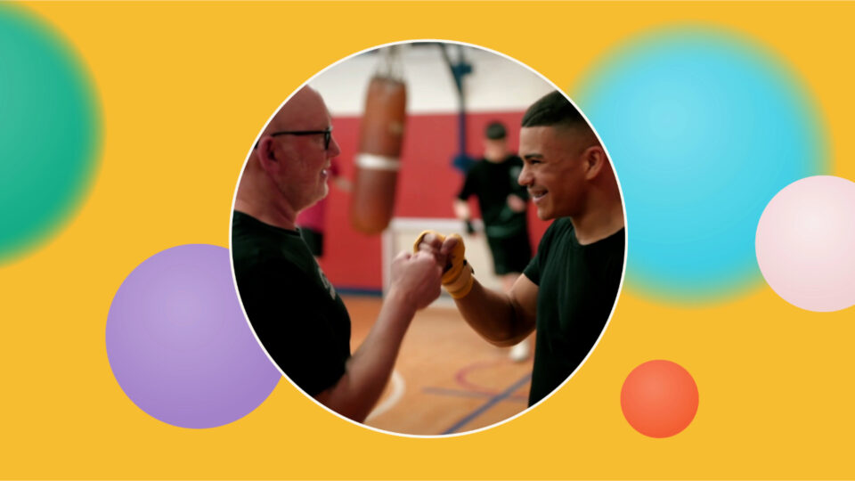 A child and adult fistbump in a boxing gym